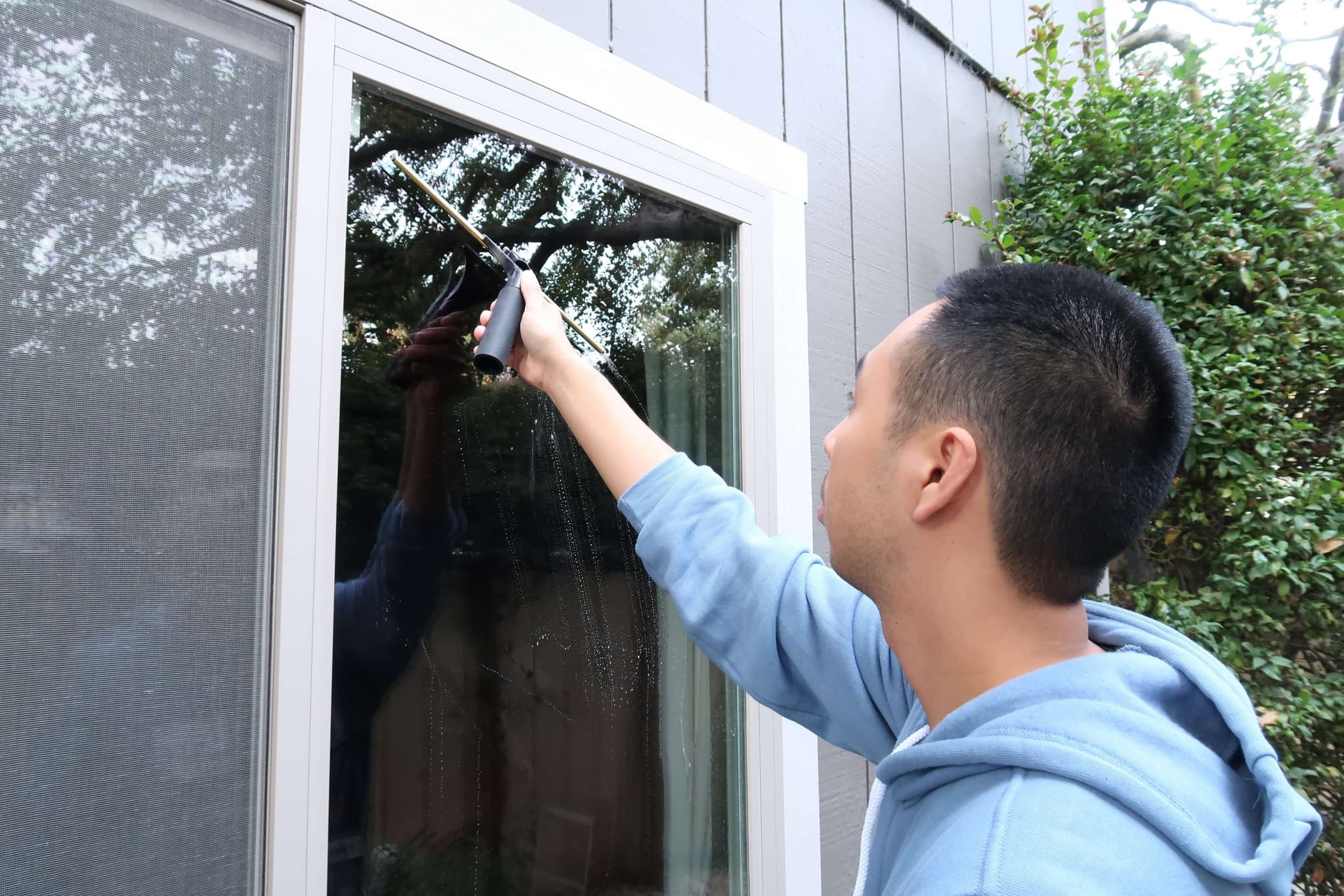 Hand detailing an exterior window with a squeegee